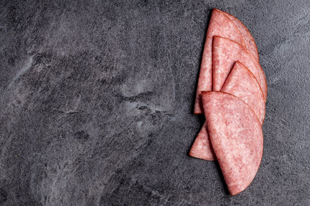 Sliced smoked salami on black table. Top view.の写真素材