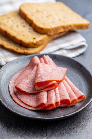 Sliced smoked salami on plate on black table.の写真素材