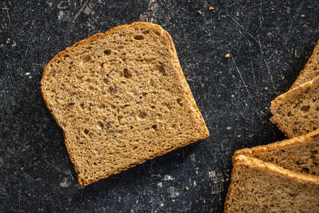 Sliced wholegrain bread on black table. Top view.