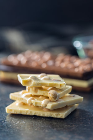 White chocolate bar with hazelnuts on black table.の写真素材