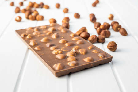 Chocolate bar with hazelnuts on white table.の写真素材
