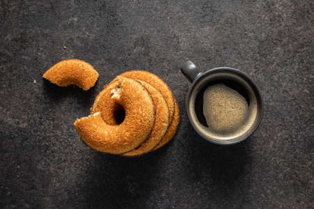 Round sponge cake dessert. Sweet donut with coffee cup on black table. Top view.の写真素材