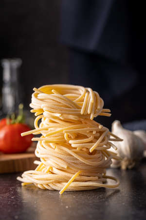 Italian pasta nest. Uncooked spaghetti nest on black table.の写真素材