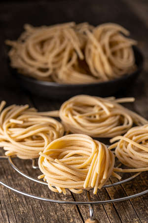 Italian pasta nest. Uncooked spaghetti nest on old wooden table.の写真素材