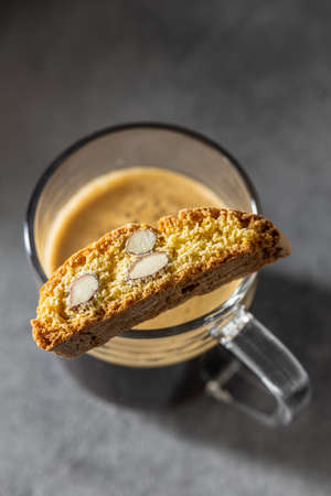 Italian cantuccini cookies and coffee cup. Sweet dried biscuits with almonds on kitchen table.の写真素材