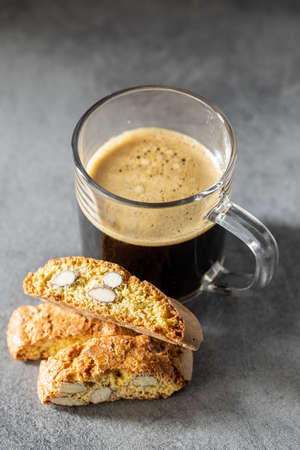 Italian cantuccini cookies and coffee cup. Sweet dried biscuits with almonds on kitchen table.の写真素材