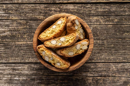 Italian cantuccini cookies in wooden bowl. Sweet dried biscuits with almonds on wooden table. Top view.の写真素材