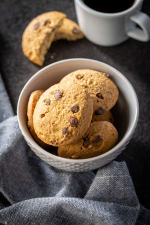 Sweet chocolate cookies. Tasty biscuits in bowl on black table.