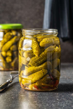 Small pickles. Marinated pickled cucumbers in jar on kitchen table.