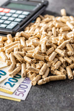 Wooden pellets, euro banknotes and calculator. Ecologic heating.の写真素材
