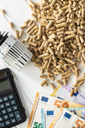 Ecological heating. Wooden pellets, euro banknotes, calculator and thermostatic head. Top view.の写真素材