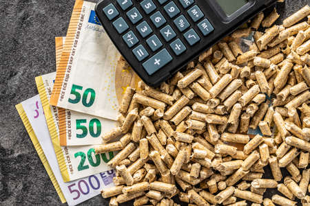 Wooden pellets, euro banknotes and calculator. Ecologic heating. Top view.の写真素材