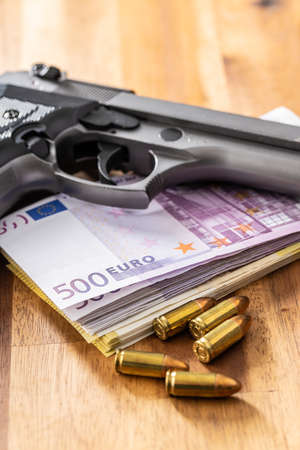 Euro banknotes with handgun and bullets on wooden table.の写真素材