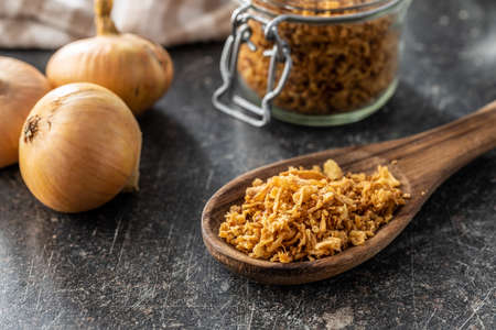 Pieces of fried onions in wooden spoon.の写真素材