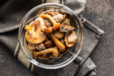 Sliced preserved mushrooms in bowl on black table. Top view.の写真素材