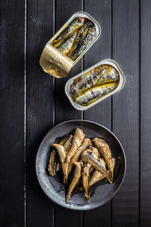 Canned sardines and sprats. Sea fish in tin can on black table. Top view.の写真素材