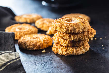 Sweet coconut cookies. Tasty biscuits with coconut flavor on black table.