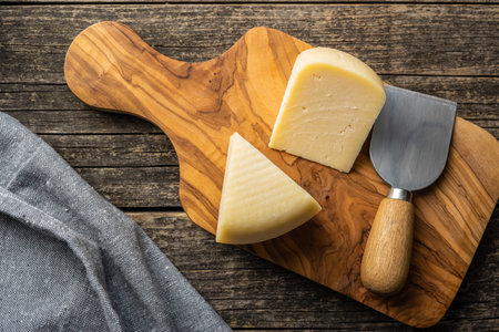 Block of hard cheese. Sliced cheese on cutting board. Top view.の写真素材