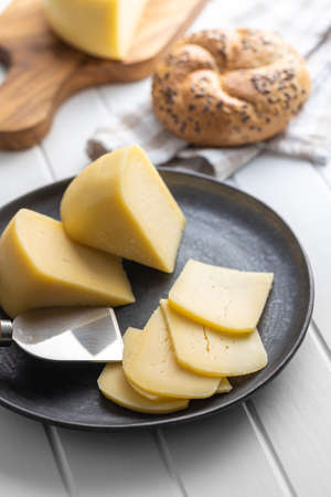 Block of hard cheese. Sliced cheese on plate.の写真素材
