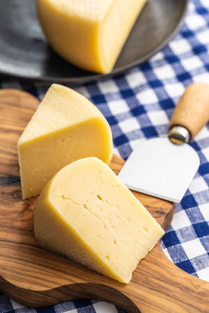 Block of hard cheese. Sliced cheese on cutting board.の写真素材