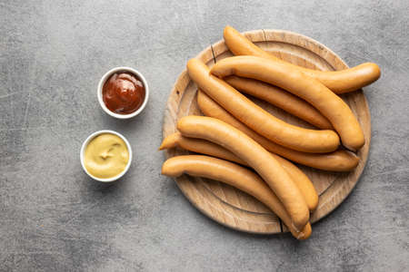 Smoked frankfurter sausages on cutting board on kitchen table. Top view.の写真素材