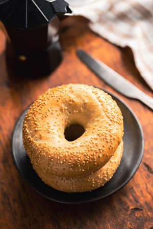 Baked bagel with sesame seeds on wooden table.