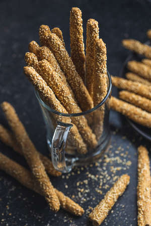 Breadsticks grissini. Bread sticks with sesame seeds on black table.の写真素材