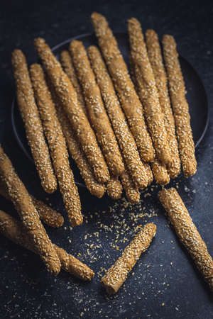 Breadsticks grissini. Bread sticks with sesame seeds on black table.