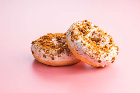 Sweet glazed donut with sprinkles on pink background.