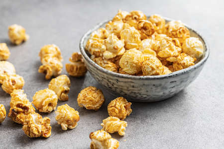 Sweet caramel popcorn in bowl on gray table.の写真素材