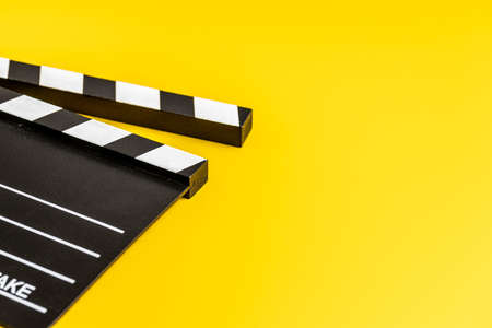 Black clapper board on yellow background.の写真素材