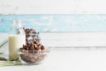 Sweet chocolate breakfast cereal flakes in bowl on kitchen table.