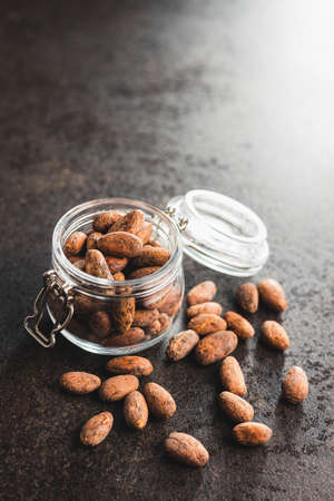 Dried cocoa beans. Cacao beans in jar on kitchen table.