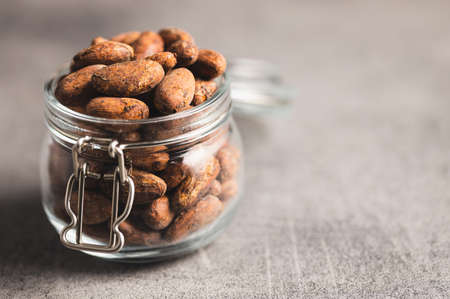 Dried cocoa beans. Cacao beans in jar on kitchen table.