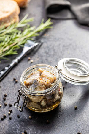 Chopped marinated fish. Salted herring in jar on black table.の写真素材