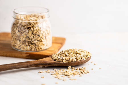 Breakfast cereals. Uncooked oatmeal. Raw oat flakes in wooden spoon.の写真素材