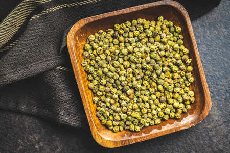 Dried green peppercorn. Dry green pepper spice in bowl on a black table. Top view.の写真素材