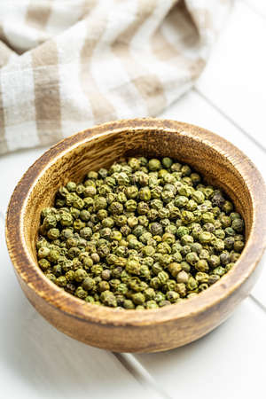 Dried green peppercorn. Dry green pepper spice in bowl on a white table.の写真素材