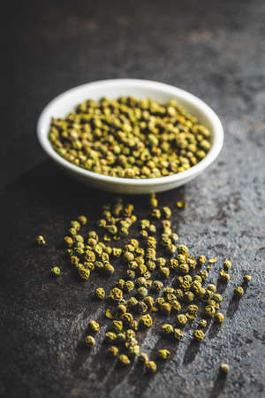 Dried green peppercorn. Dry green pepper spice on black table.の写真素材
