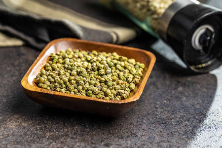 Dried green peppercorn. Dry green pepper spice in bowl on a black table.の写真素材