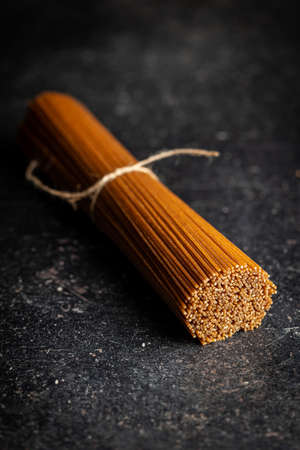 Uncooked whole grain spaghetti. Raw pasta on a kitchen table.の写真素材