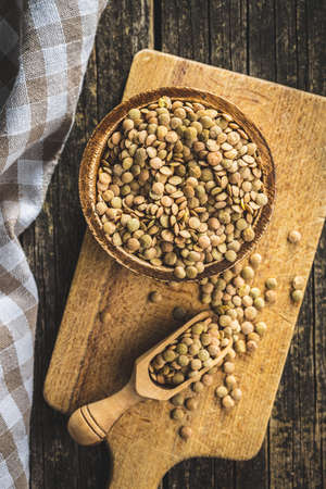 Uncooked brown lentils. Raw legume in a bowl on cutting board. Top view.の写真素材