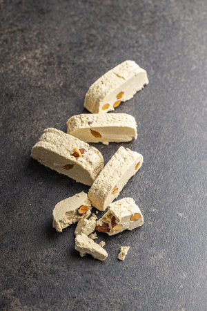 Sweet tahini halva with almonds. Turkish dessert on a kitchen table.の写真素材