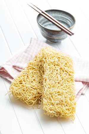 Instant noodles. Uncooked chinese noodles on a white table.の写真素材