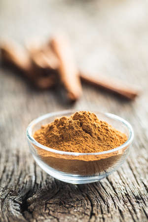 Dry cinnamon powder in bowl on a wooden table. Cinnamon spice.