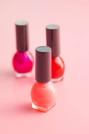 Colorful nail polish bottles on a pink background.の写真素材