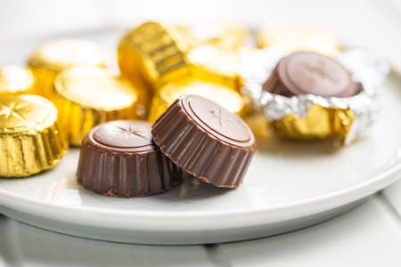 Wrapped chocolate pralines. Sweet chocolate candies on a plate.