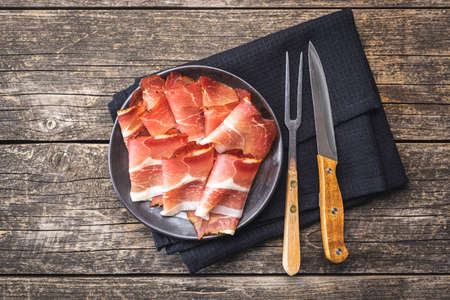 Sliced black forest ham. Dried prosciutto ham on a plate. Top view.
