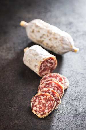 Traditional sausage with white mold. Dried pork salami on a black table.