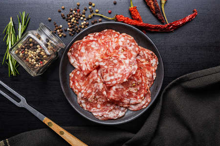 Sliced italian salami sausage with peppercorn on a plate. Top view.